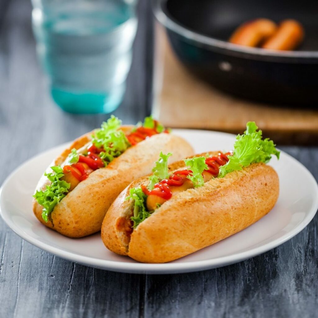 Twee smakelijke hotdogs van DoyDoy, geserveerd met heerlijke toppings en knapperige broodjes.